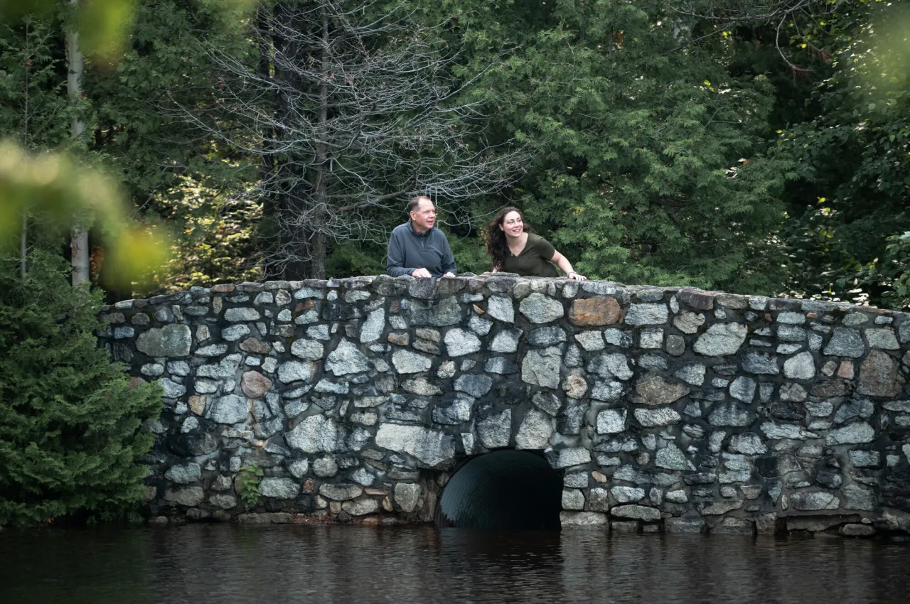 Two people stand atop a cobble-stone bridge.