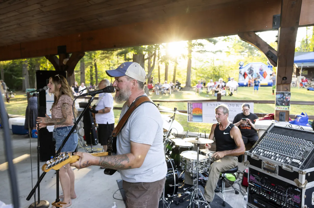 A band plays in a pavilion with a large crowd.