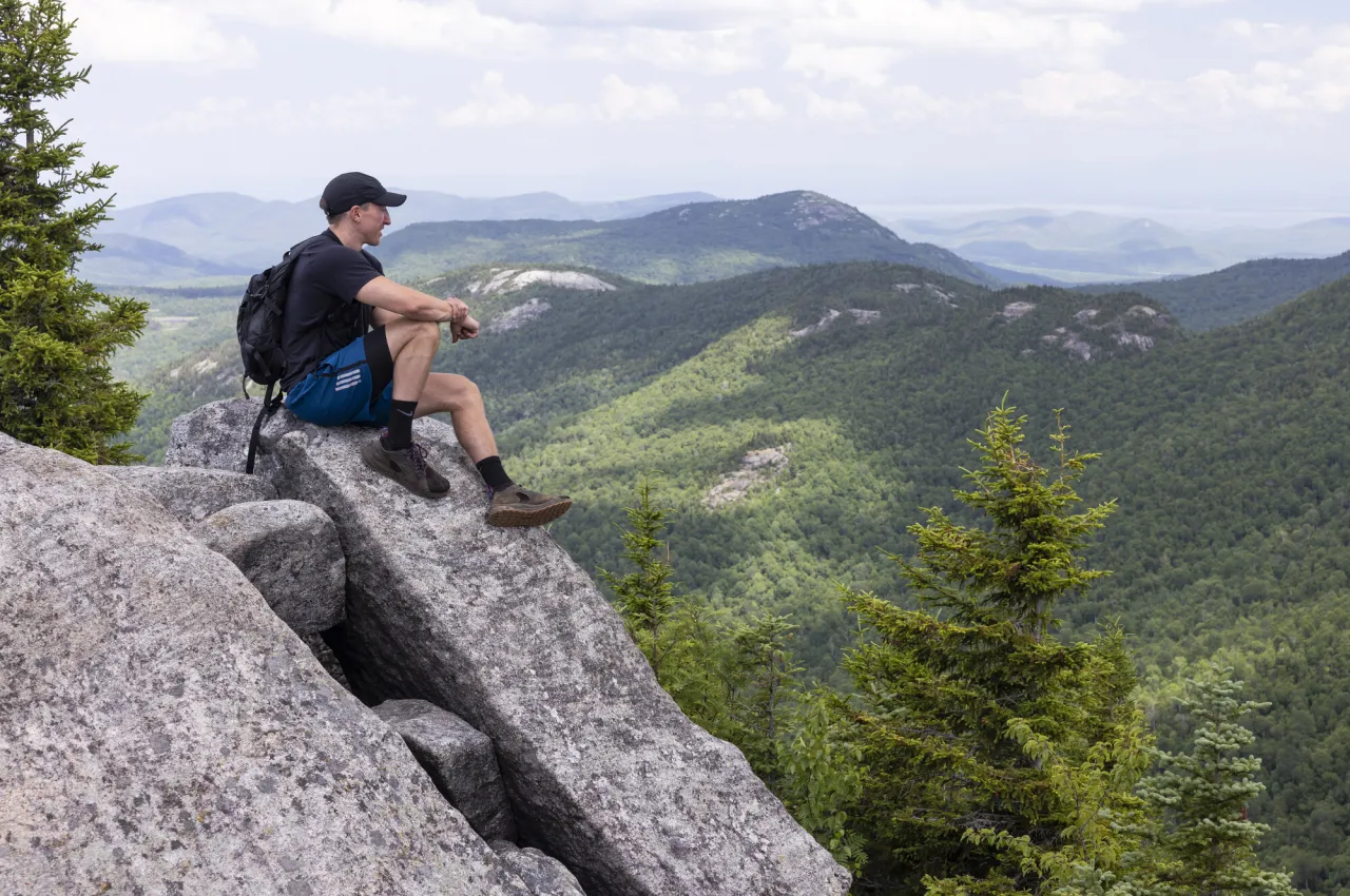 A man sits on a rock on a summit
