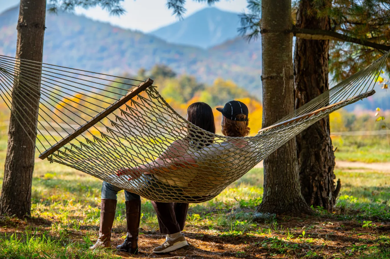 Couple sits in hammock looking at mountains