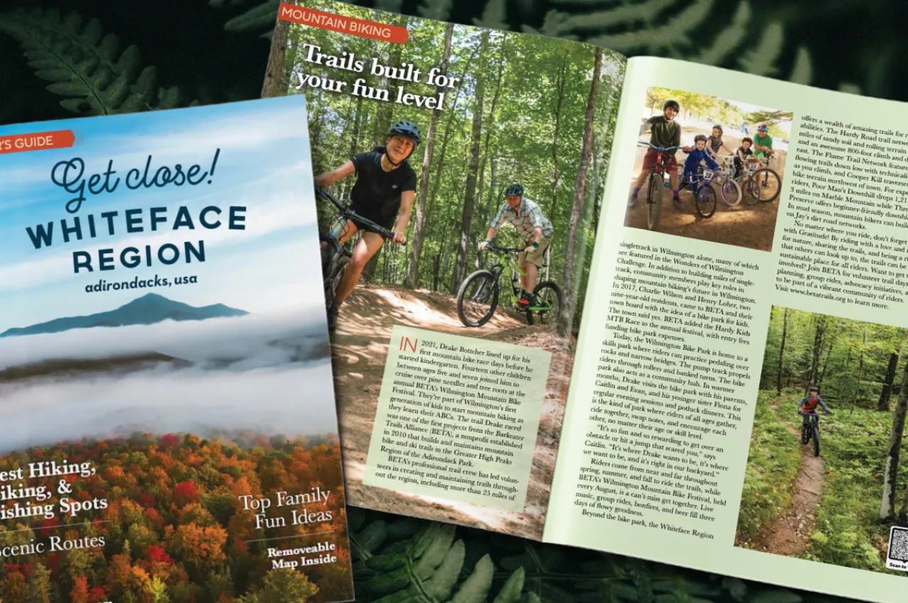 A visitor guide sits on top of an open copy of the guide, showing an array of photos. A map is the background.