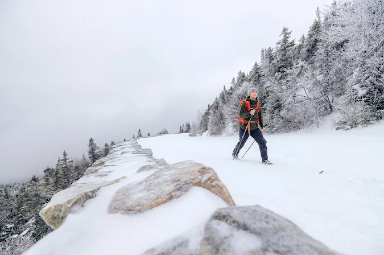 A cross-country skier going up a snow-covered mountain road in the winter.