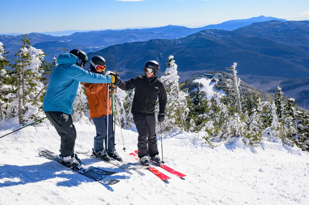 Skiers fist bump on the slope.