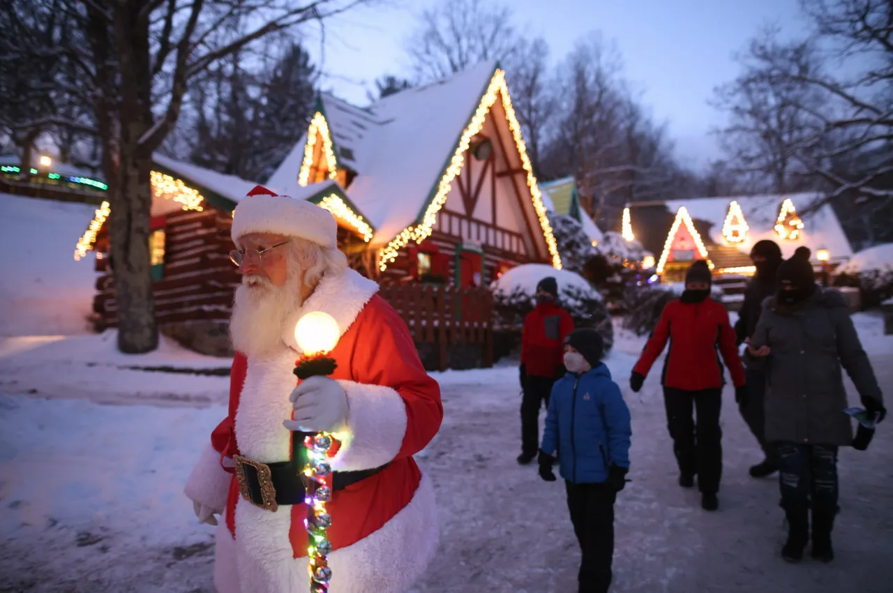 Man dressed as Santa walks with lit staff while people follow behind