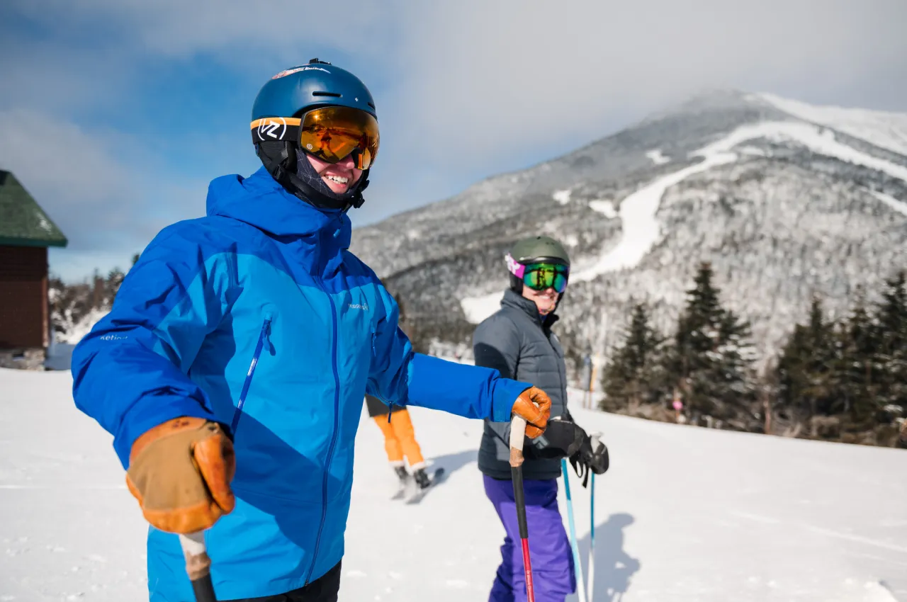 Man and woman in ski gear on slopes with Whiteface summit in background