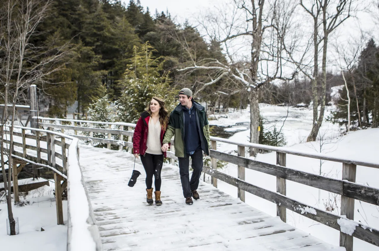 Man and woman walk together on snowy boardwalk