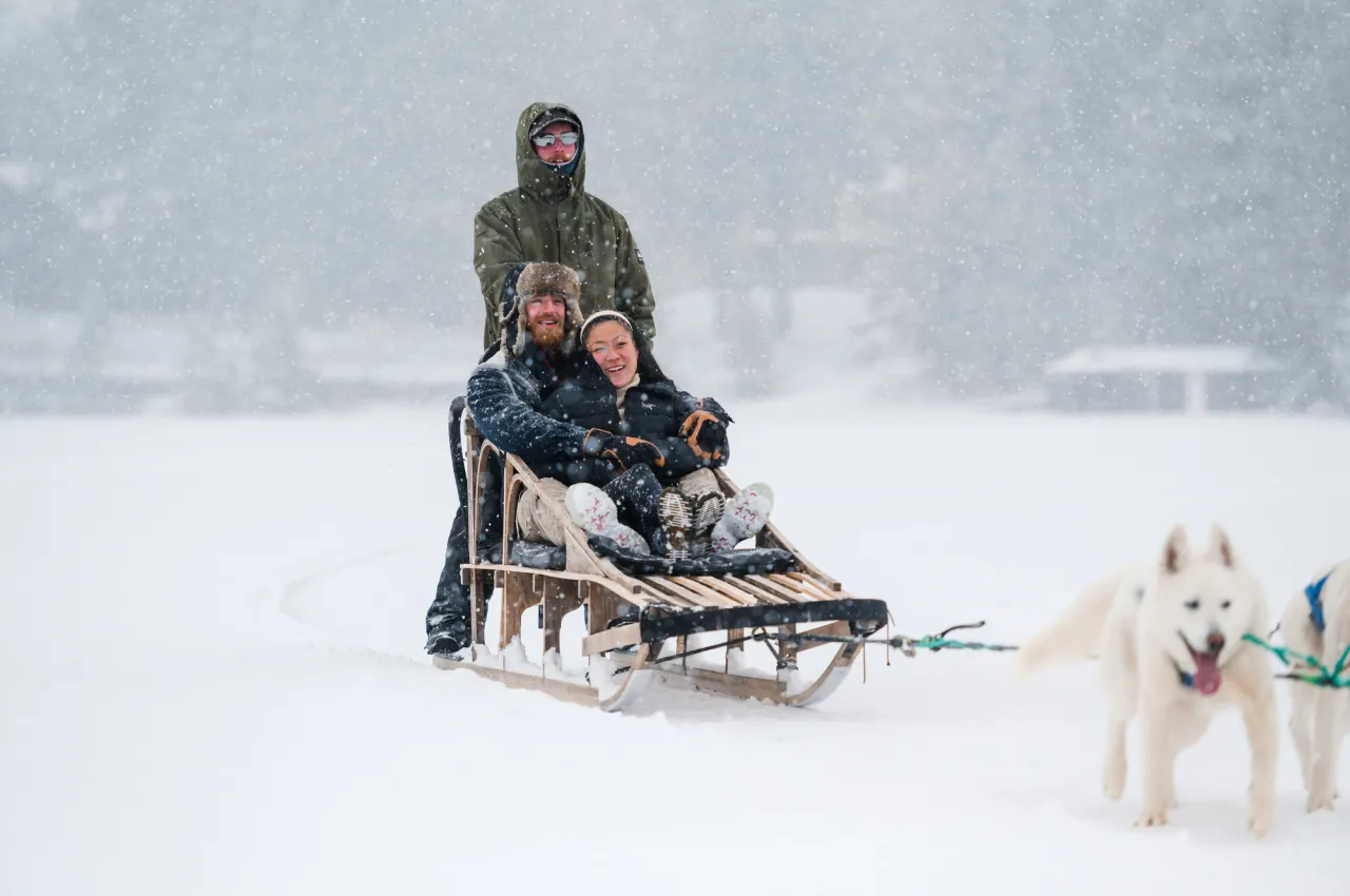 A couple takes a winter dog sled ride on Mirror Lake.