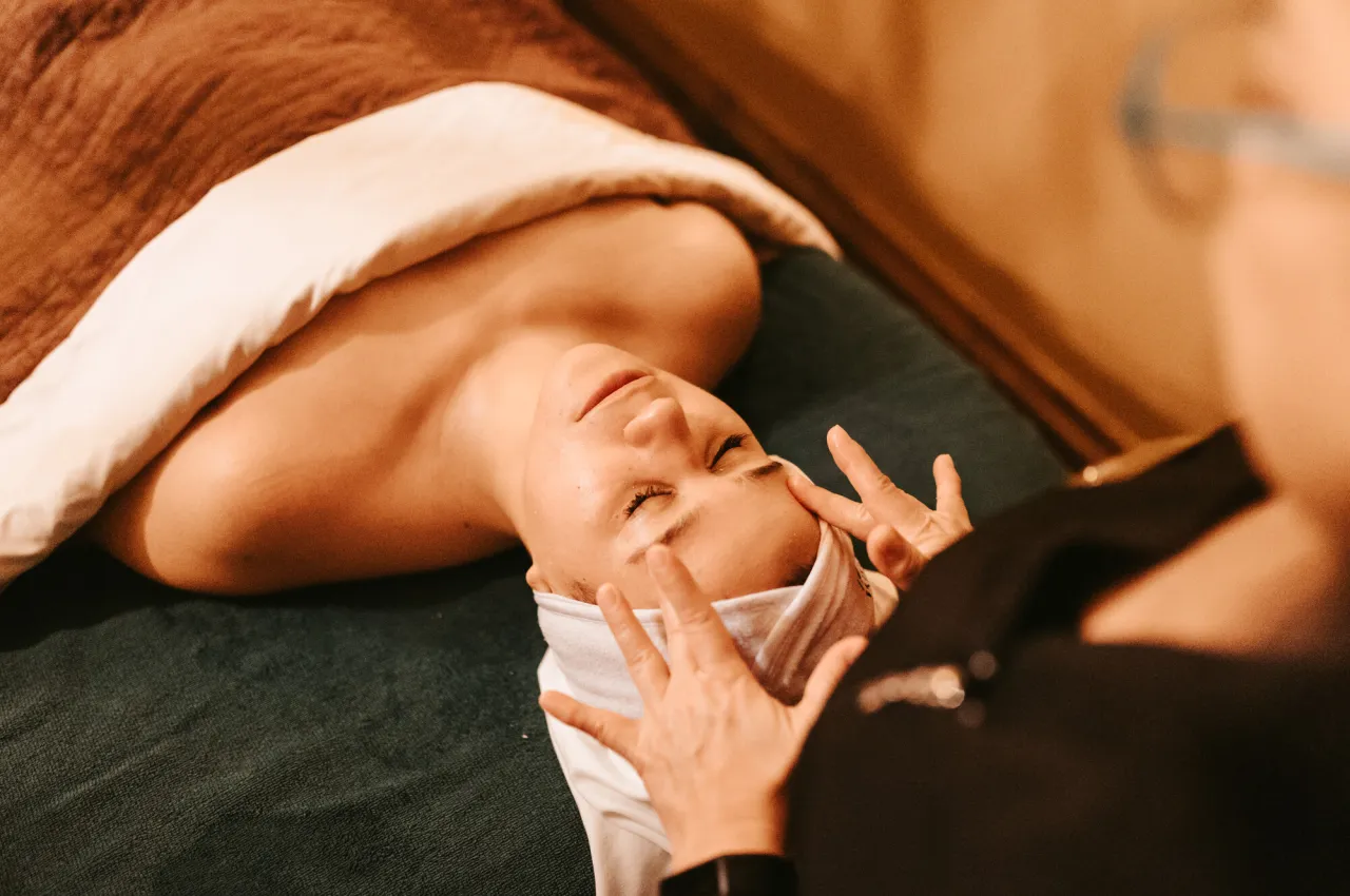 A woman in a towel receives a head massage at a spa.