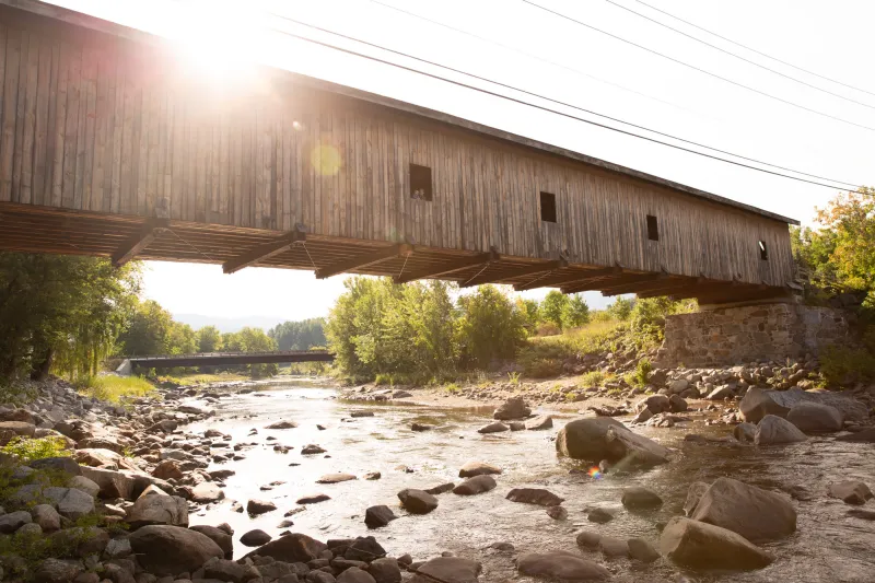 A covered bridge over a rocky stream.