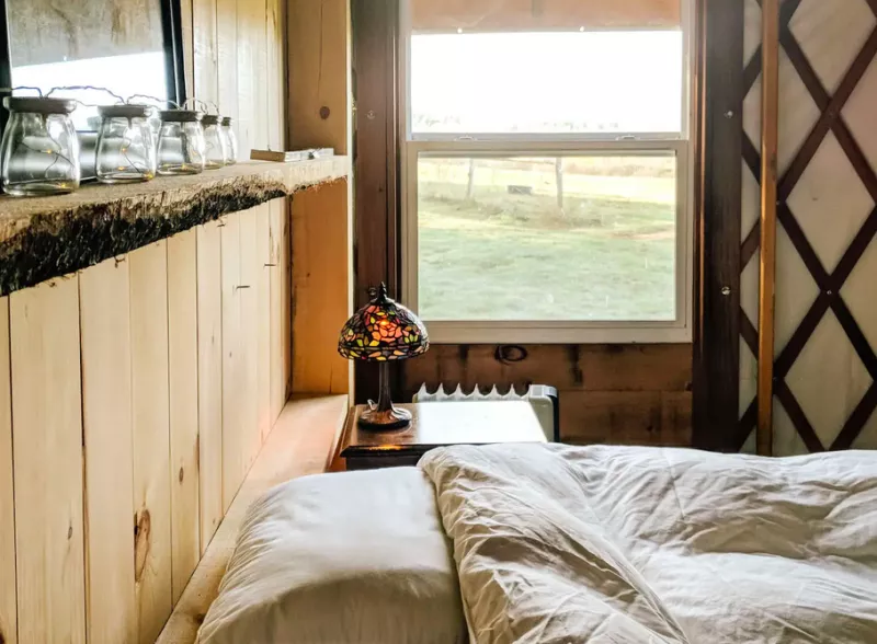 A close up of a bed and lamp in a yurt.