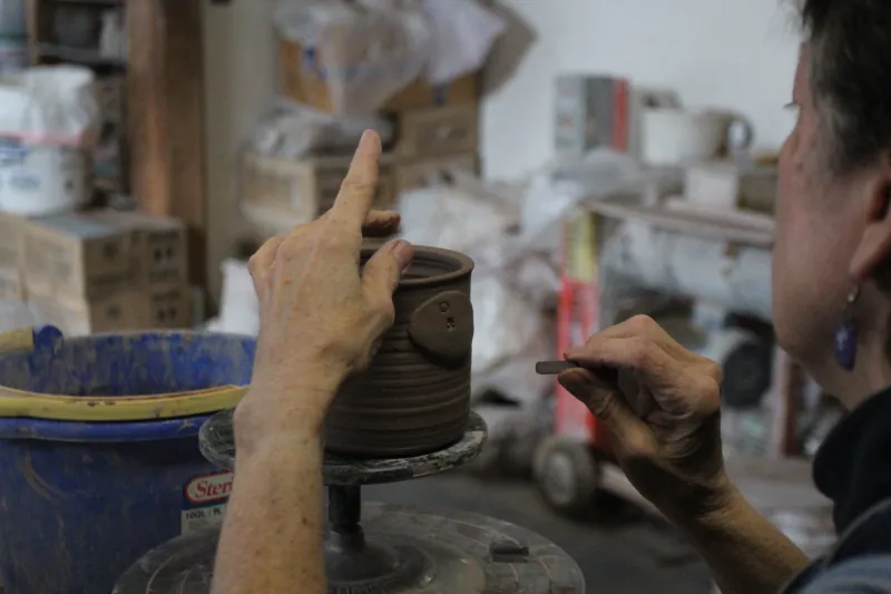 Local artist Cheri Cross putting the finishing touches on a hand made mug.