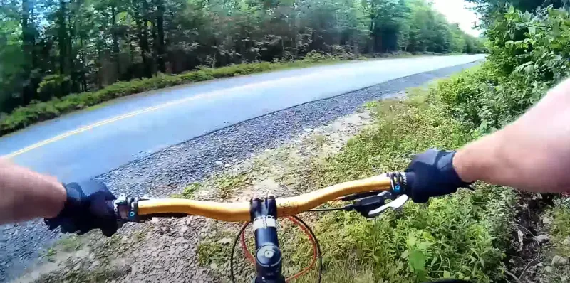 Riding a bike off the end of a trail towards a paved road