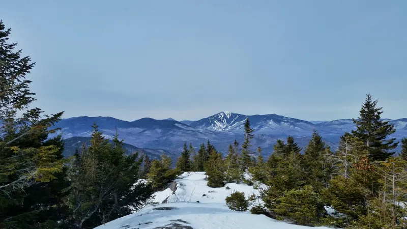 A winter view from a mountain summit with the ski trails at Whiteface visible in the distance.