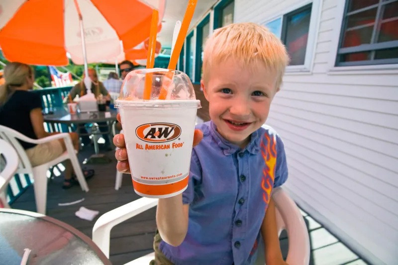 Child holds a dessert while sitting outside