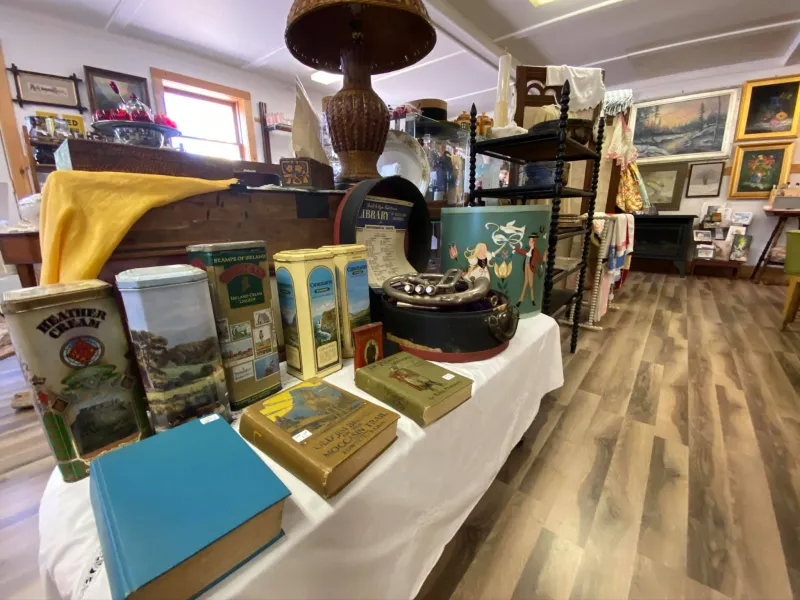 Tables and shelves of antiques on display in a brightly-lit shop.