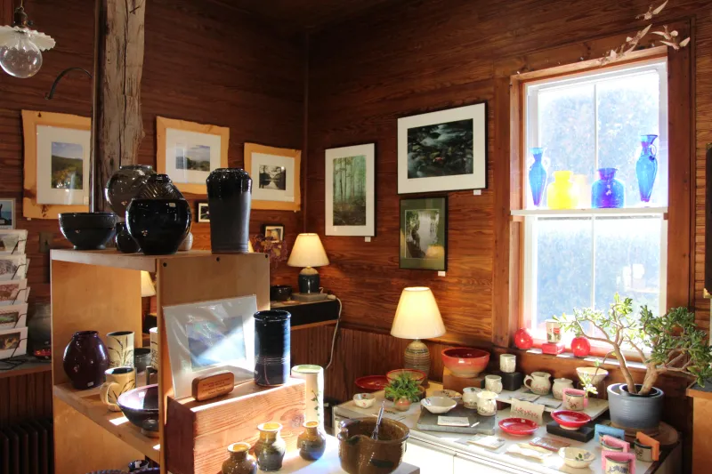 The interior of an art gallery, with pottery, glassware, and paintings on display.