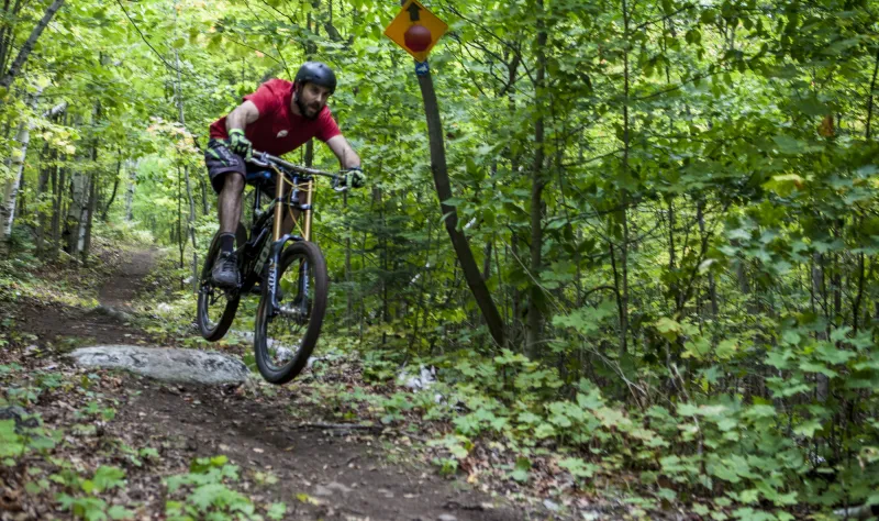 Mountain biker rides downhill over a jump