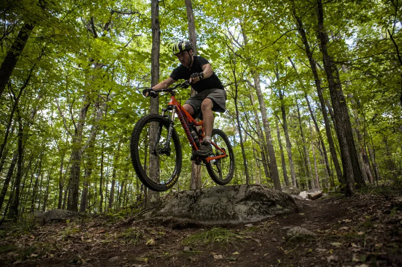 A mountain biker in air riding through the woods