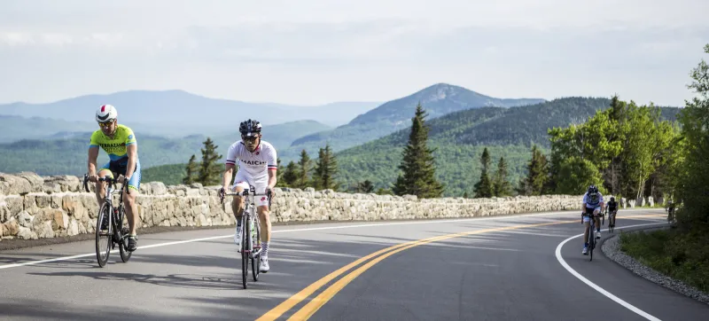 Bikers make their way up the Whiteface highway. Mountains in the backdrop.