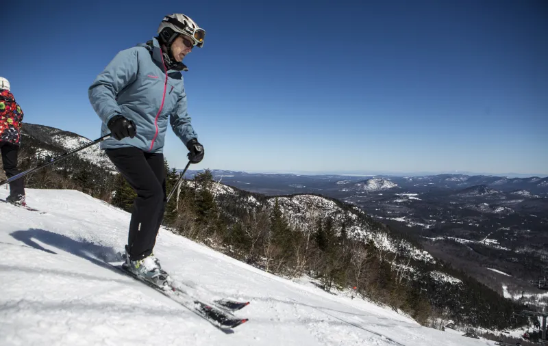 A skier at the top of a drop off, preparing to ski down.