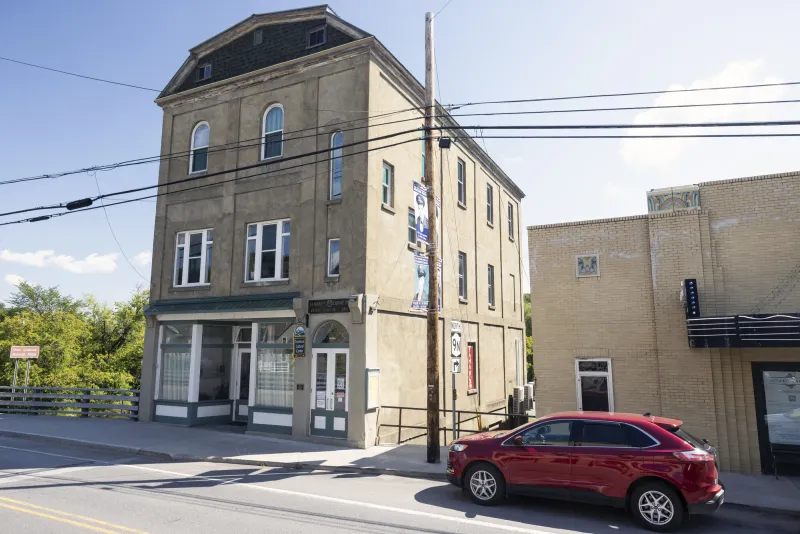 The Tahawus Center as seen from main street. A red SUV is parked out front and to the right is an old movie theater.