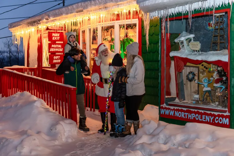 Family stands with Santa outside North Pole building