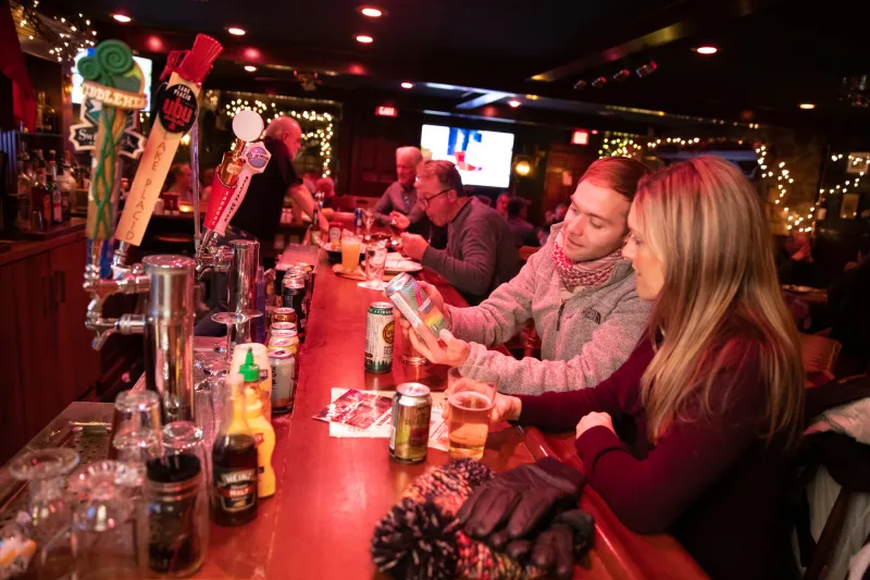 Two people order at a dimly lit bar