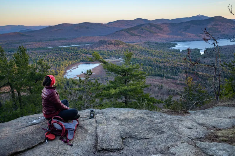 A dog and its owner look at the sunset on top of Silver Lake Mountain