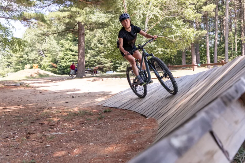 A cyclist wearing a helmet rides a mountain bike on a bike ramp