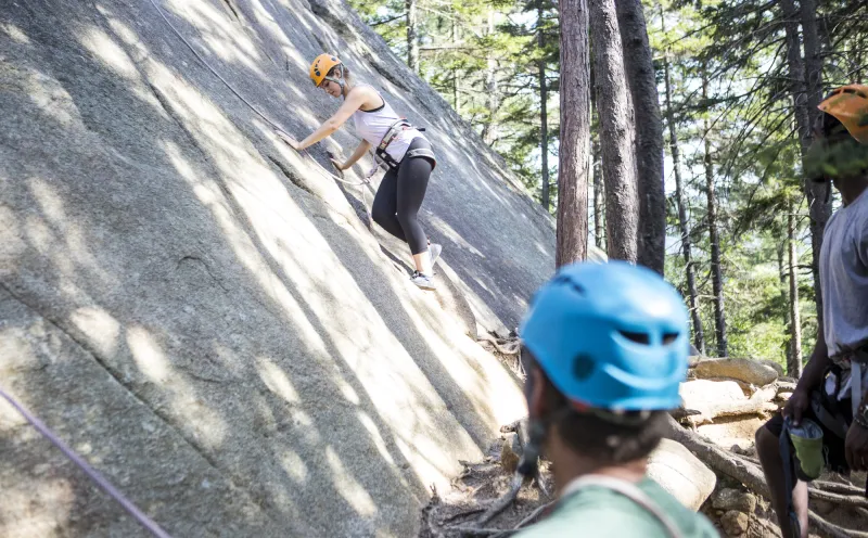 A climber works her way up the beginning of a slabby route