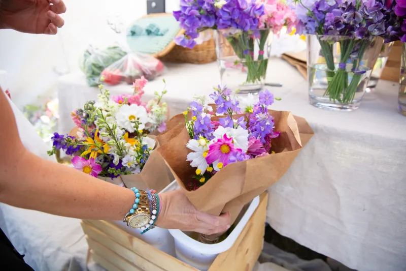 A woman picks a floral bouquet from a stand.