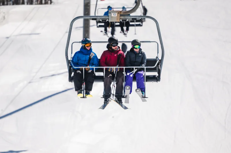 Three skiers ride the lift at Whiteface Mountain
