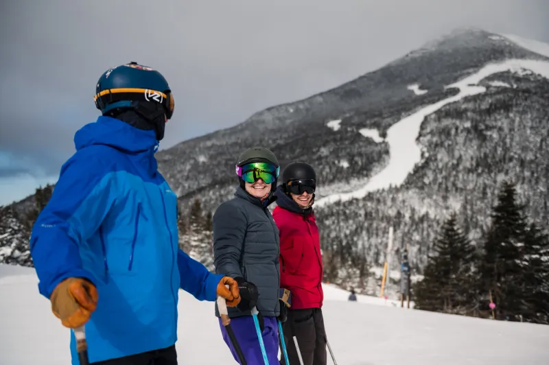 Three skiers rest on a groomed trail at Whiteface Mountain