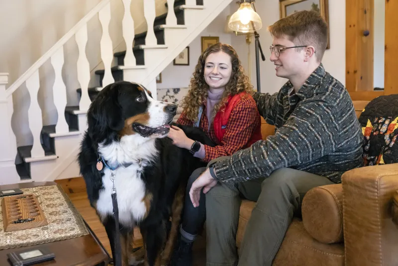 Two people and a dog rest comfortably in an indoor living space at Whiteface Farm