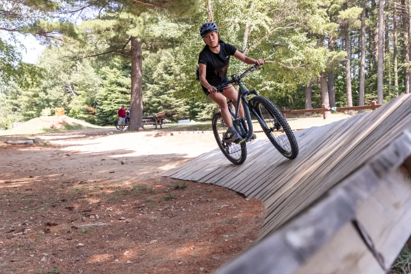 A cyclist rides on a curving wooden skills ramp.