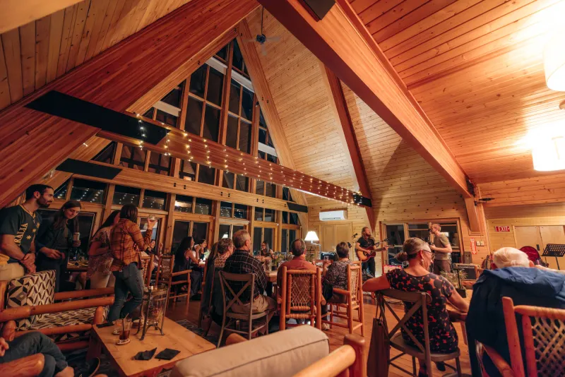 A large wooden A-frame room full of people listening to music