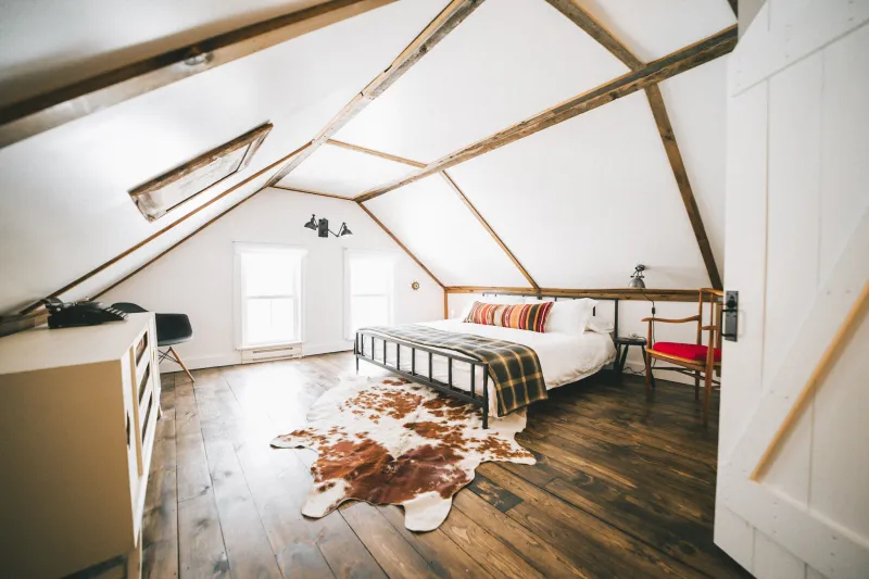 A lit rustic room with a cowhide rug and old furniture.