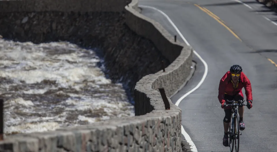 A biker rides alongside a raging river