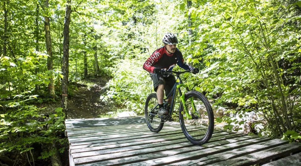 A mountain biker rides across a wooden bridge.