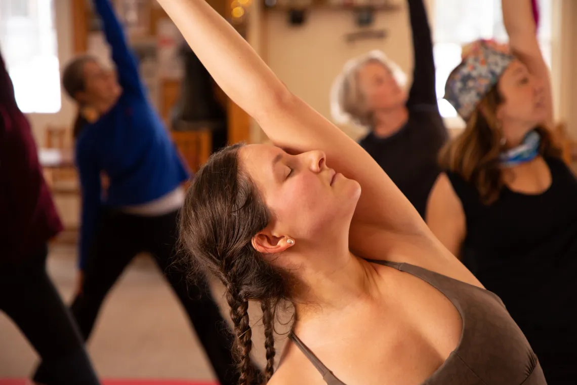 A woman stretches in a yoga class indoors.