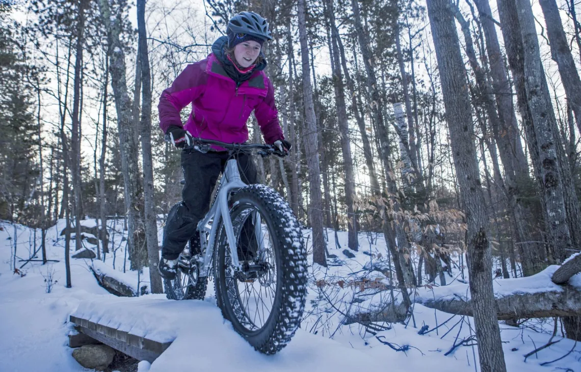 Person fat tire biking in snow over bridging