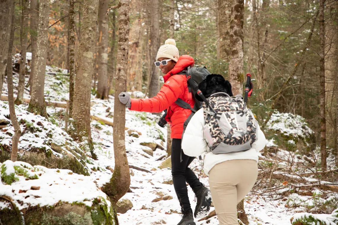 Two hikers in winter gear hike up trail