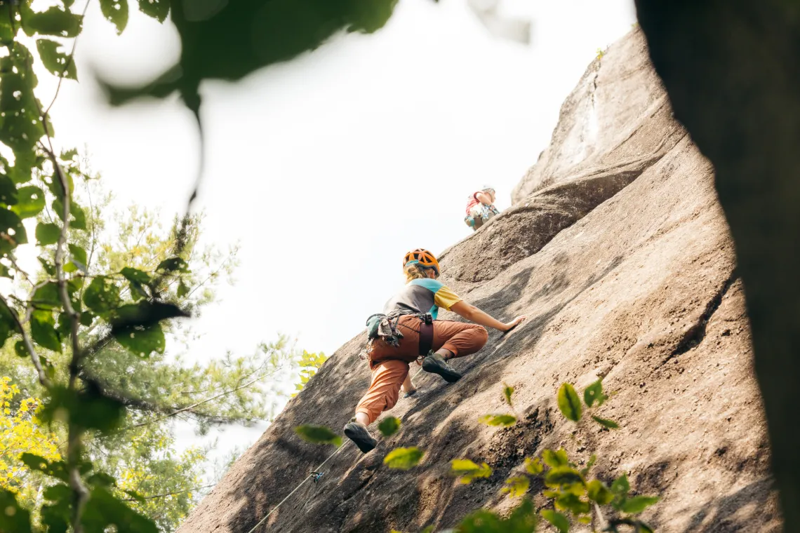 Climbers ascending rock wall seen from below