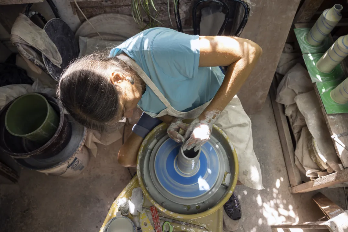 A person works with clay on a wheel